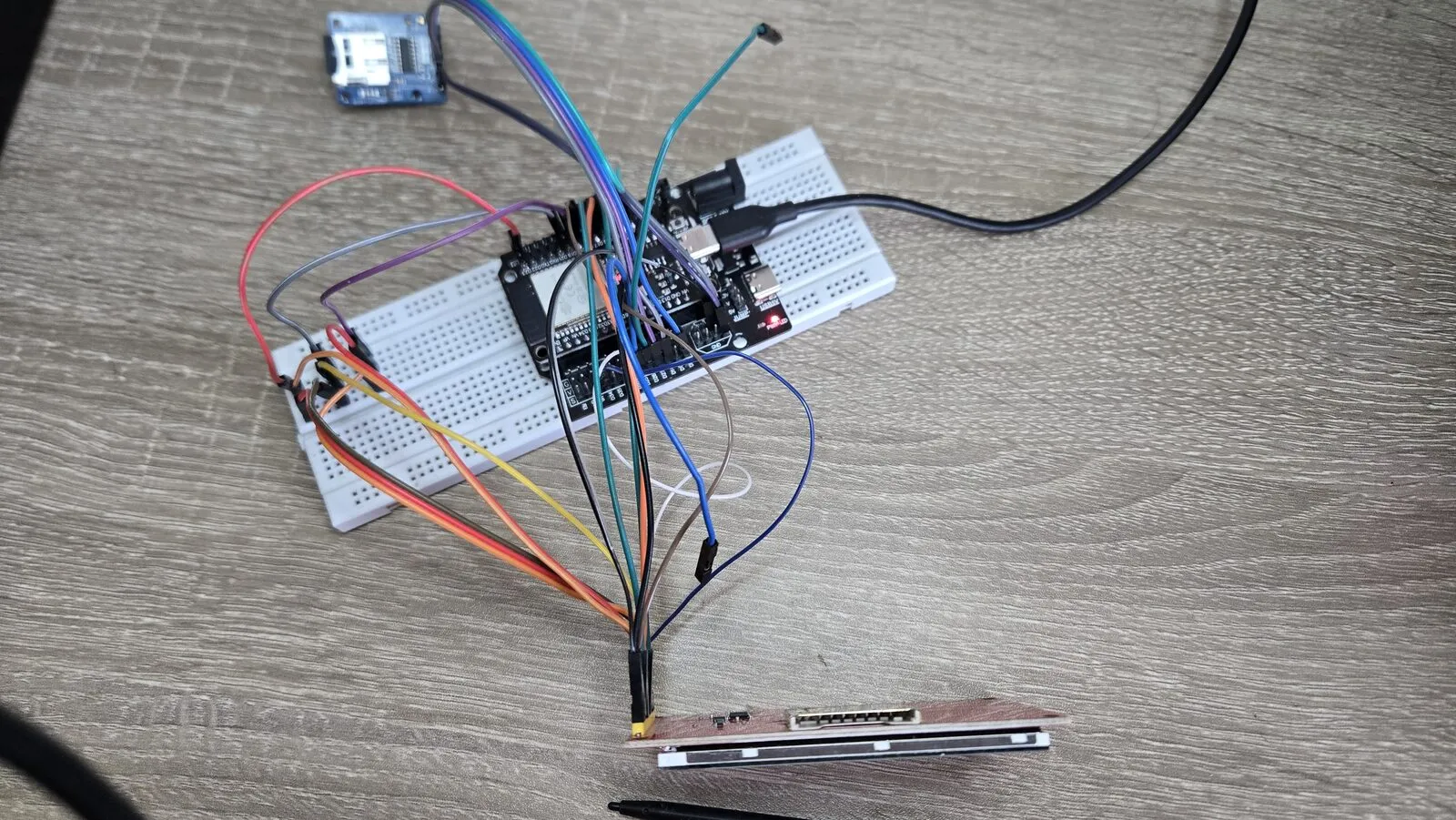 The ESP32 on a breadboard, wired with jumper wires to the LCD and a microSD card module
